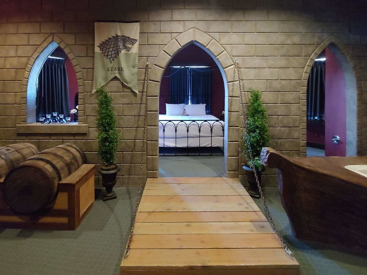A room made to look like an old English castle with a fake drawbridge, a bathtub that looks like a boat, and fake wine barrels