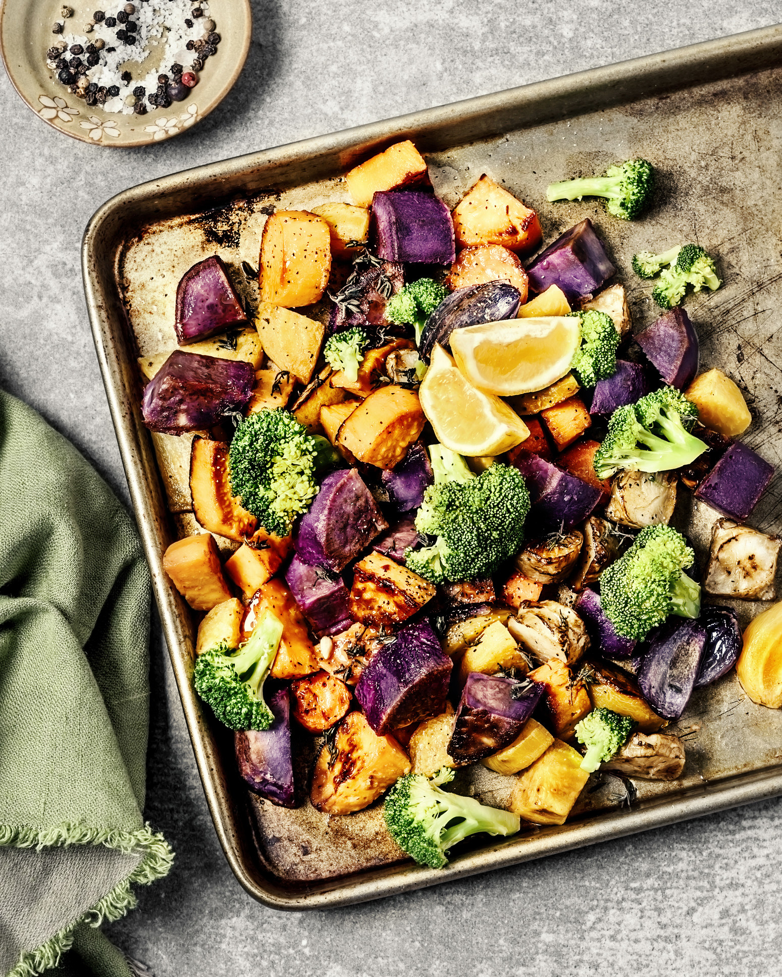 A sheet pan of different roasted veggies like broccoli and sweet potato.