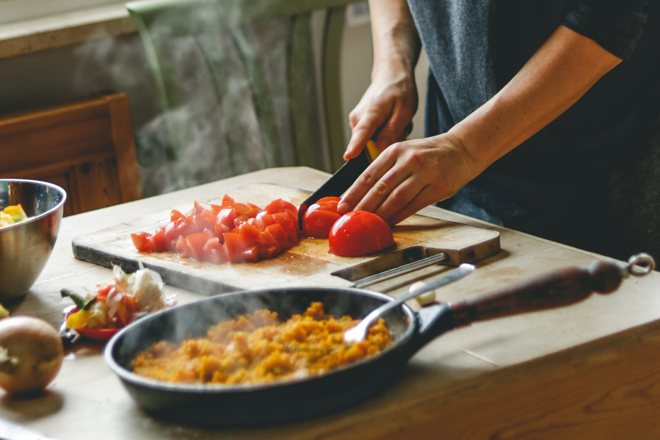 A woman cooking rice and tomatoes.