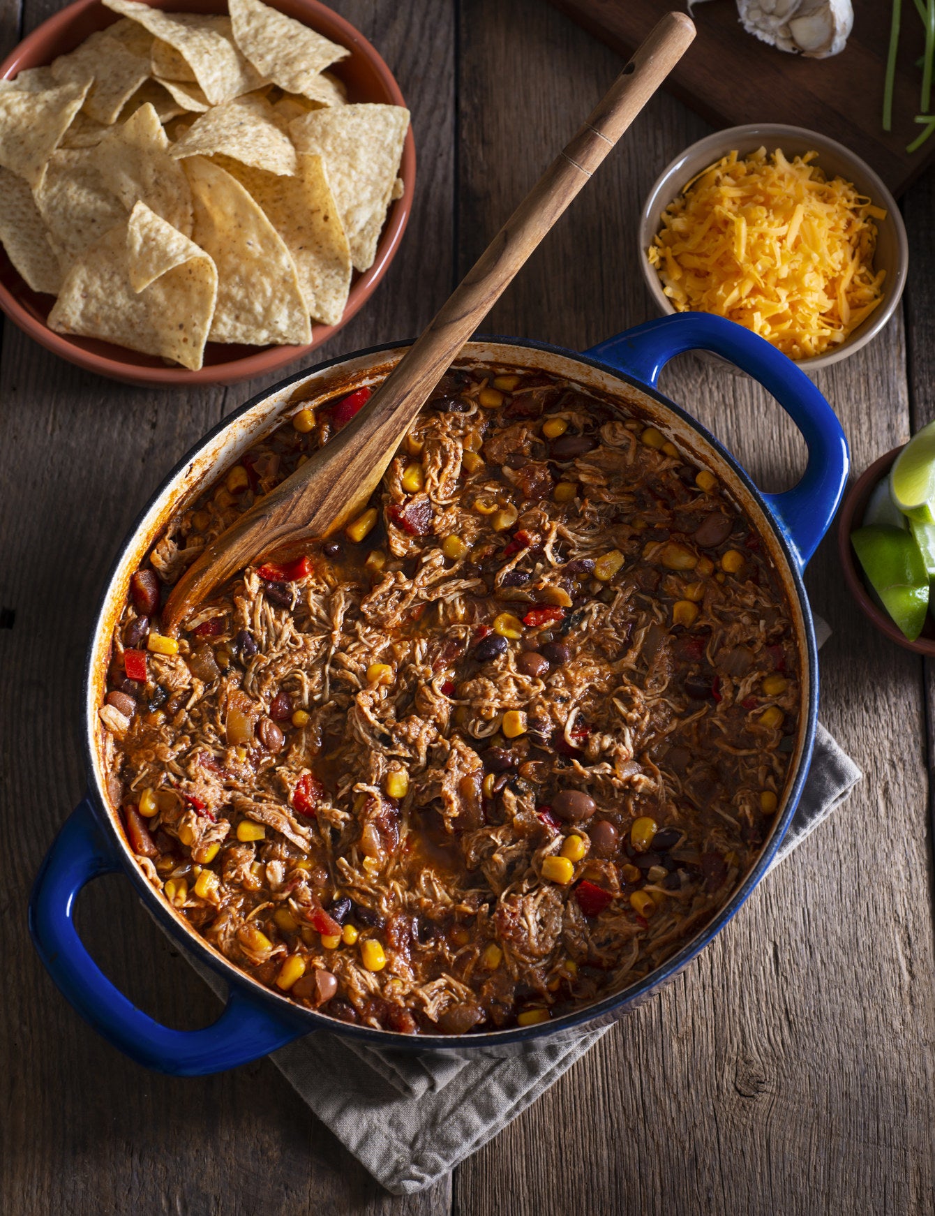 A big pot of chili with shredded chicken and cheese.