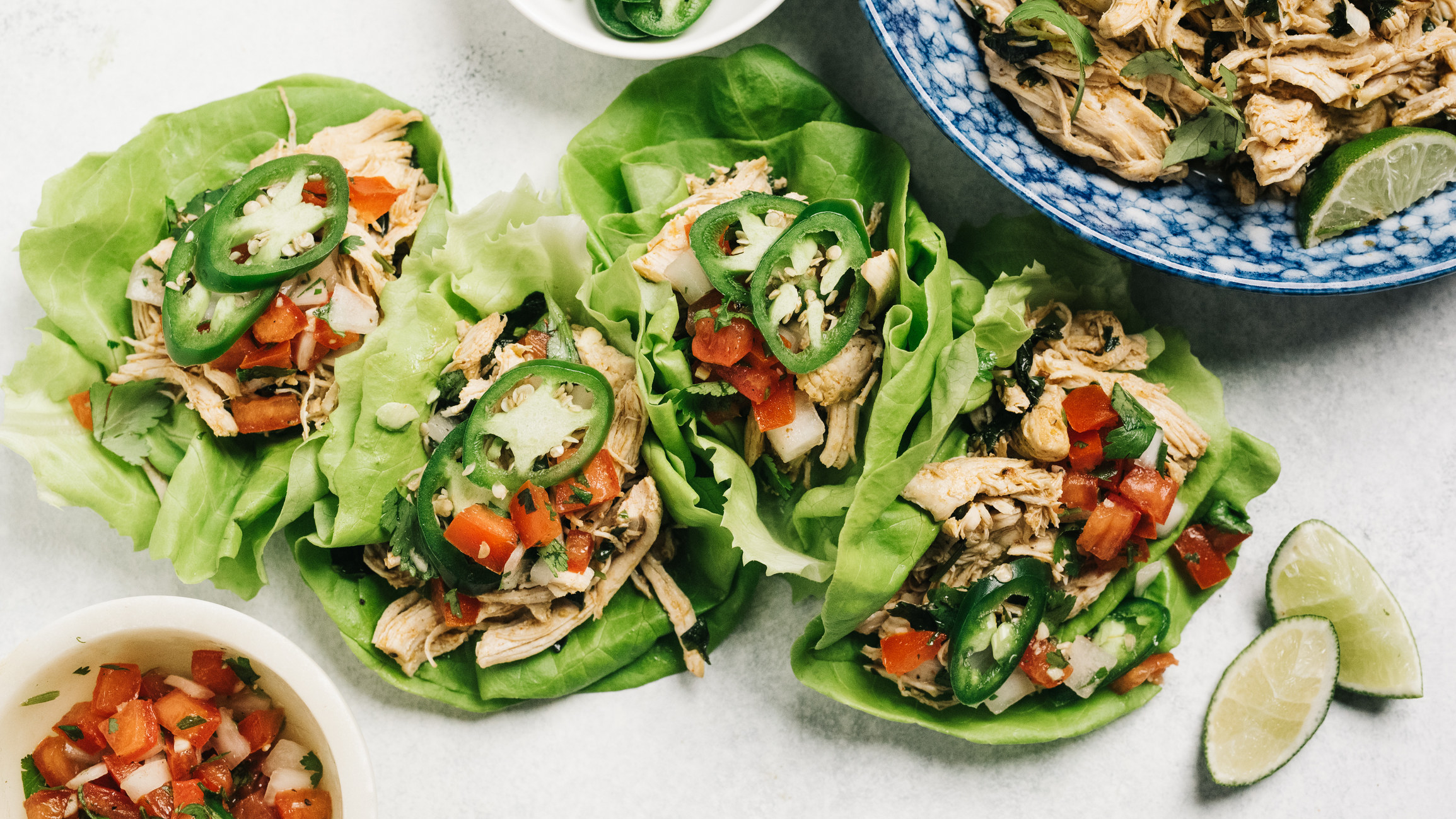 Lettuce wraps made from shredded chicken topped with veggies.