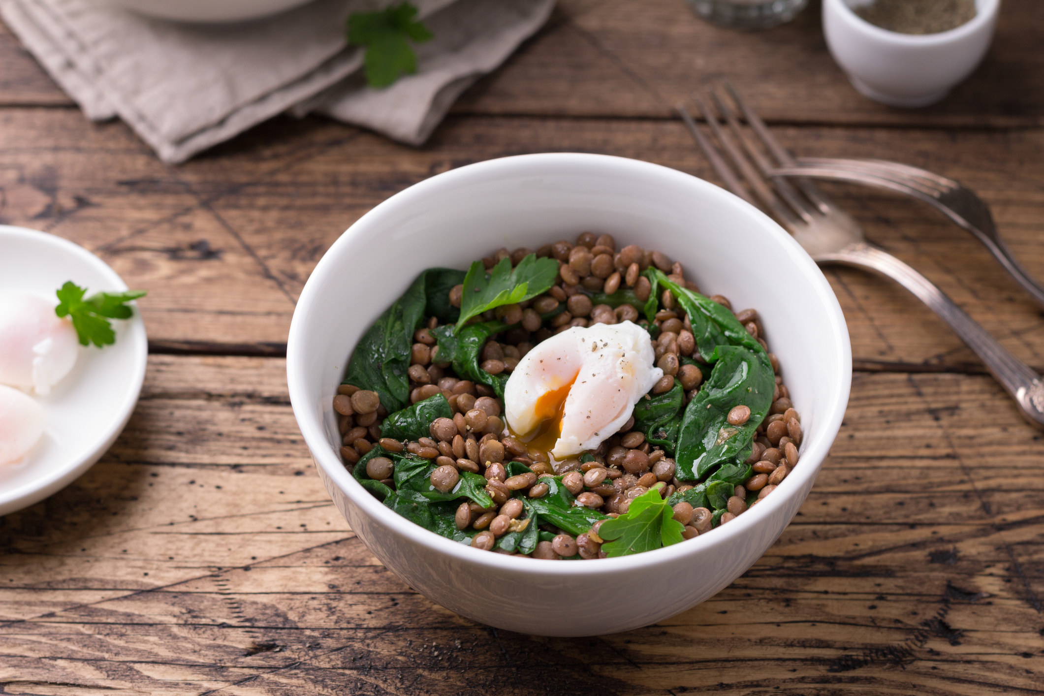 A bowl of lentils with greens and a poached egg.