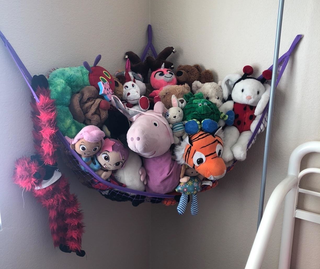 reviewer photo showing all their stuffed animals in a purple hammock 