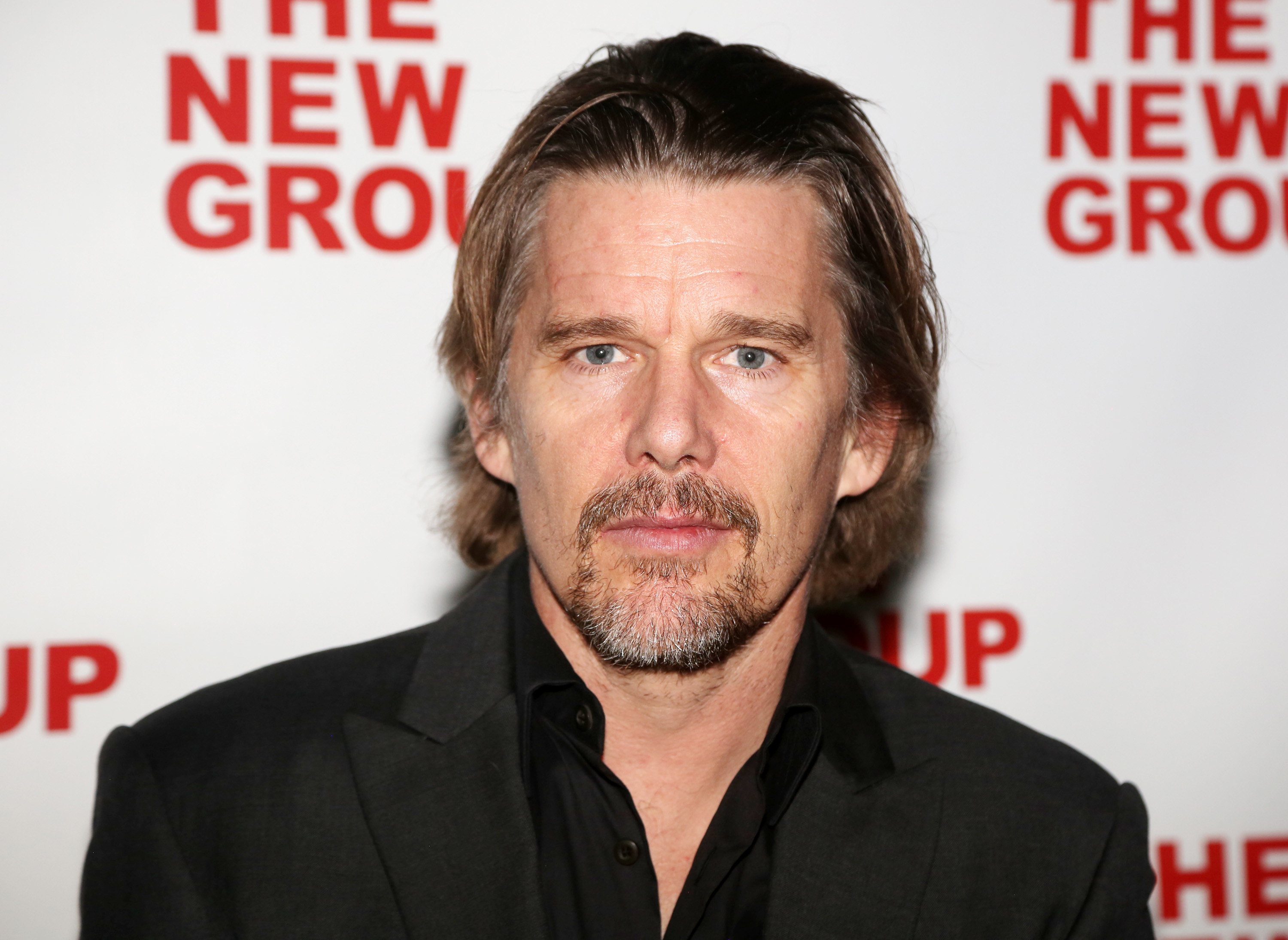 Ethan Hawke in a black shirt open at the collar