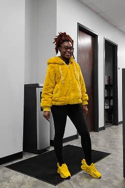 Image of reviewer in black leggings, a fluffy yellow jacket, and the sneakers in a matching yellow 