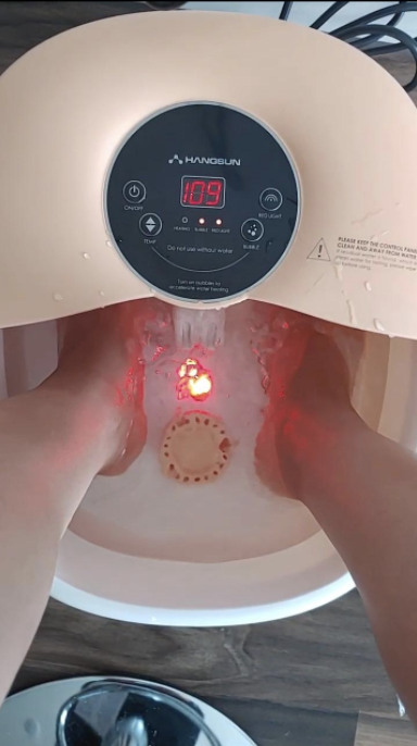 reviewer&#x27;s feet in the foot spa filled with water