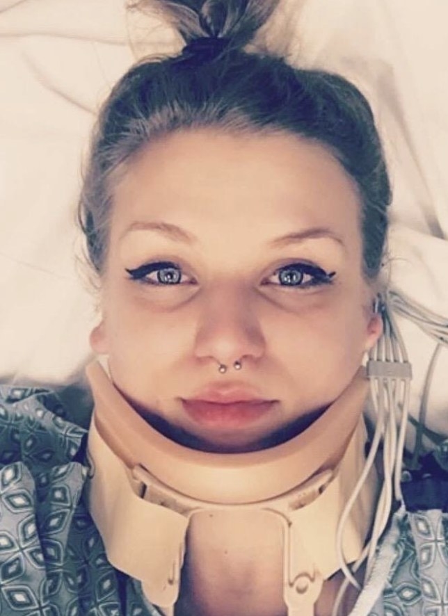 A reviewer photo in a hospital bed wearing aa neck brace and waterproof black eyeliner