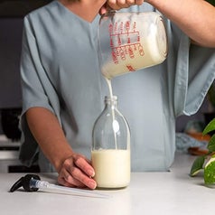 a model pouring the lotion mix into a reusable pump bottle 
