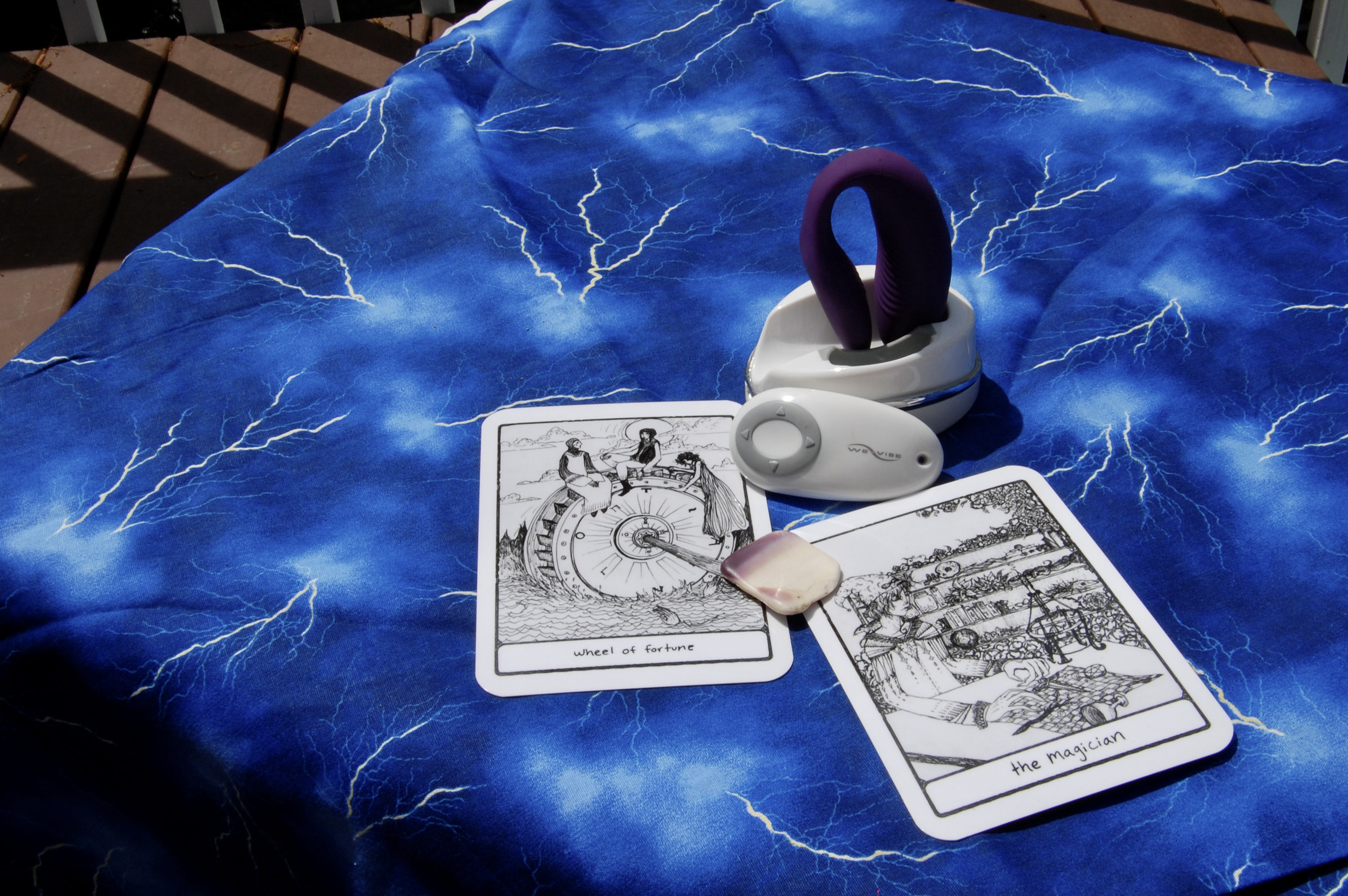 Photo of purple We-Vibe Sync with two tarot cards (the Magician and Wheel of Fortune), plus a small, square-shaped shell