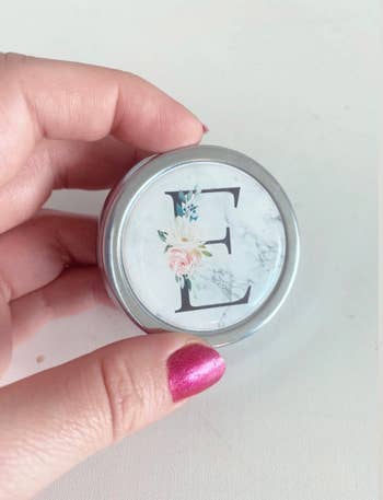 BuzzFeed editor holding up small metal round pillbox with floral monogrammed E on it 