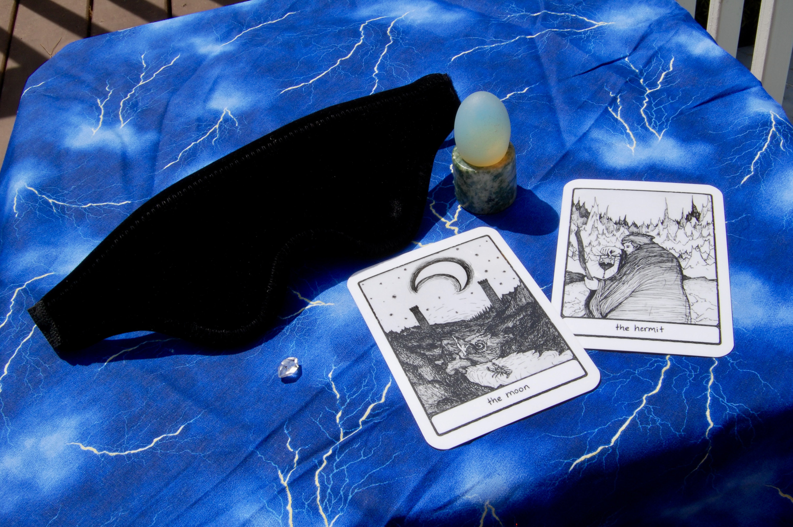 Photo of the Liberator Loveblind with two tarot cards (the Moon and the Hermit), plus a yoni egg and a small crystal