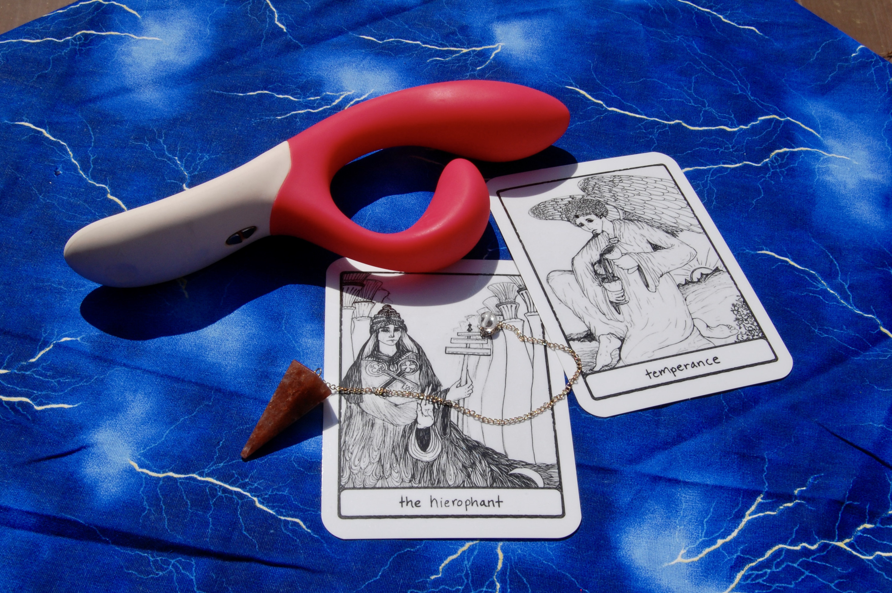 Photo of the We-Vibe Nova with two tarot cards (Temperance and the Hierophant), plus a crystal pendulum