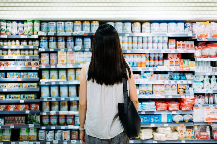 a woman staring at a shelf in a grocery store