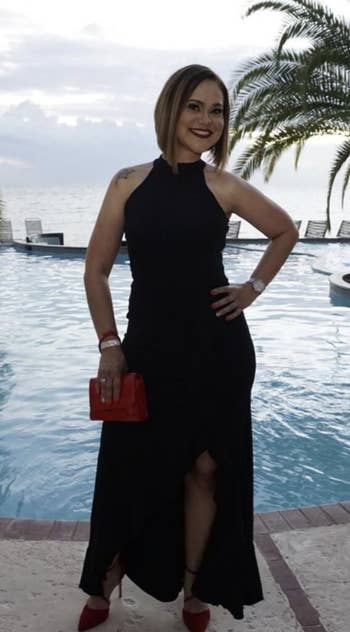 reviewer wearing a black full length cocktail dress that is sleeveless and has a slit in the skirt