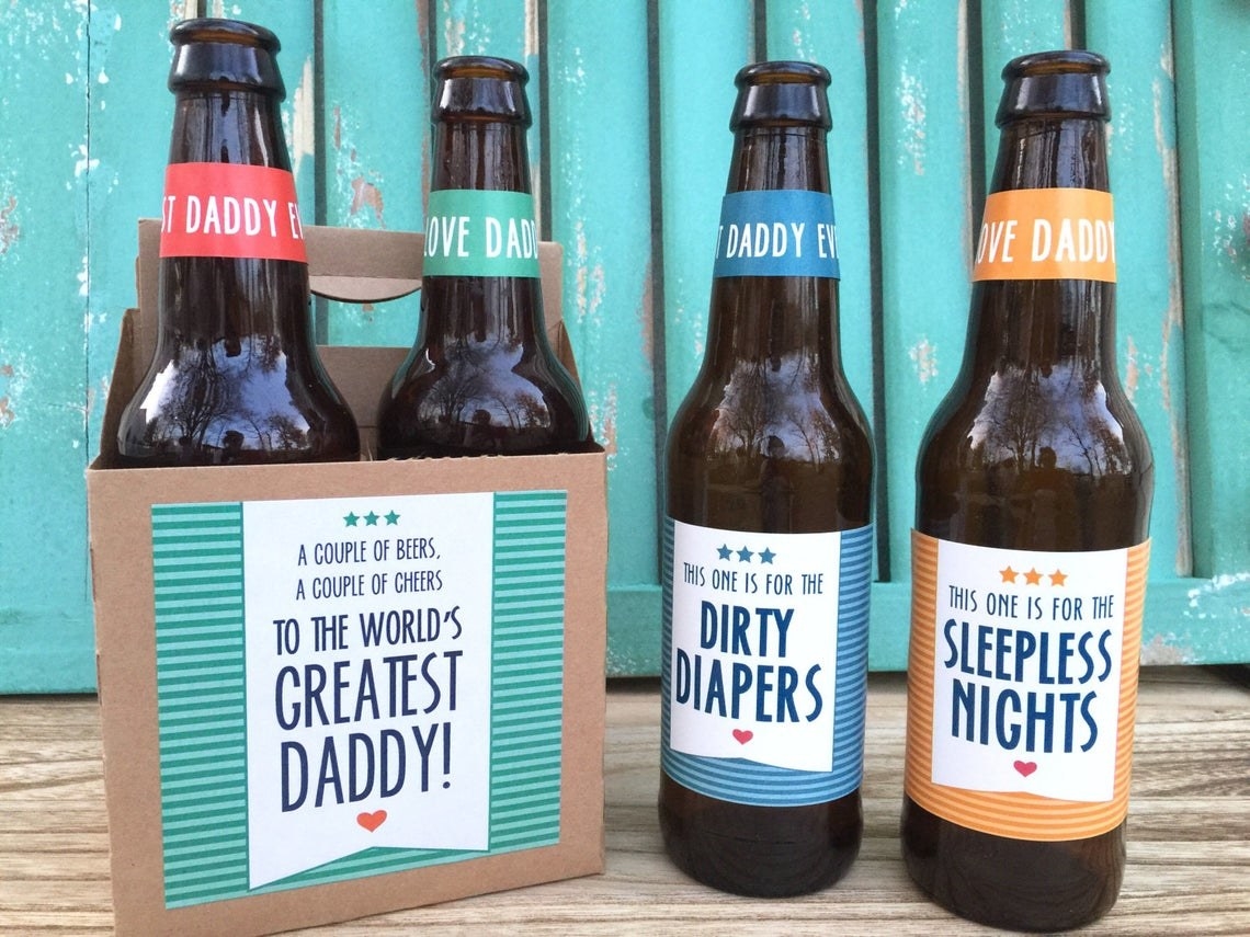 four beers with the custom labels on them and the cardboard carrier that says &quot;a couple of beers, a couple if cheers, to the world&#x27;s greatest daddy!&quot; 