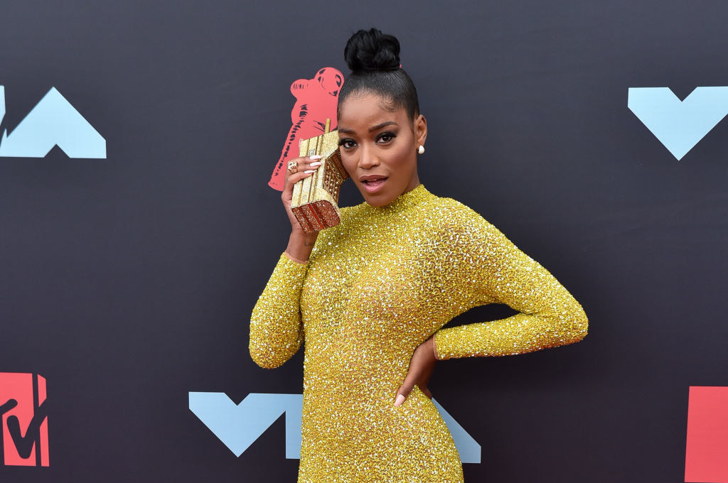 Keke holdingup a purse in the shape of a phone up to her ear on the VMAs red carpet