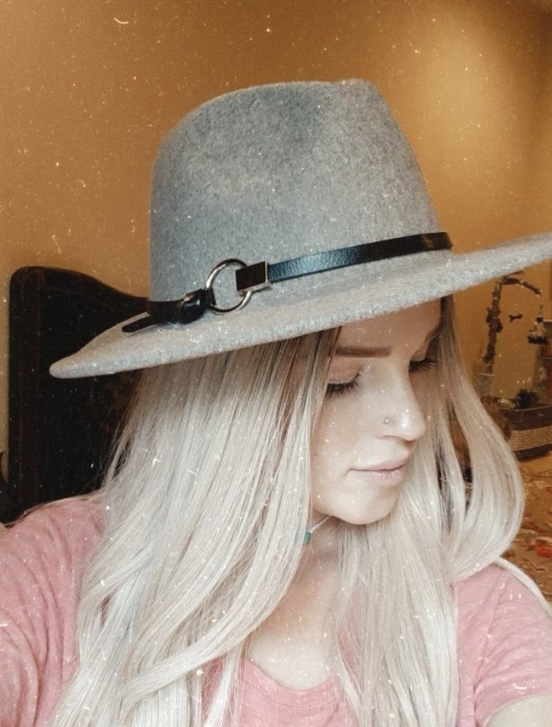 a model wearing a faux suede wide brim hat with a faux leather strap