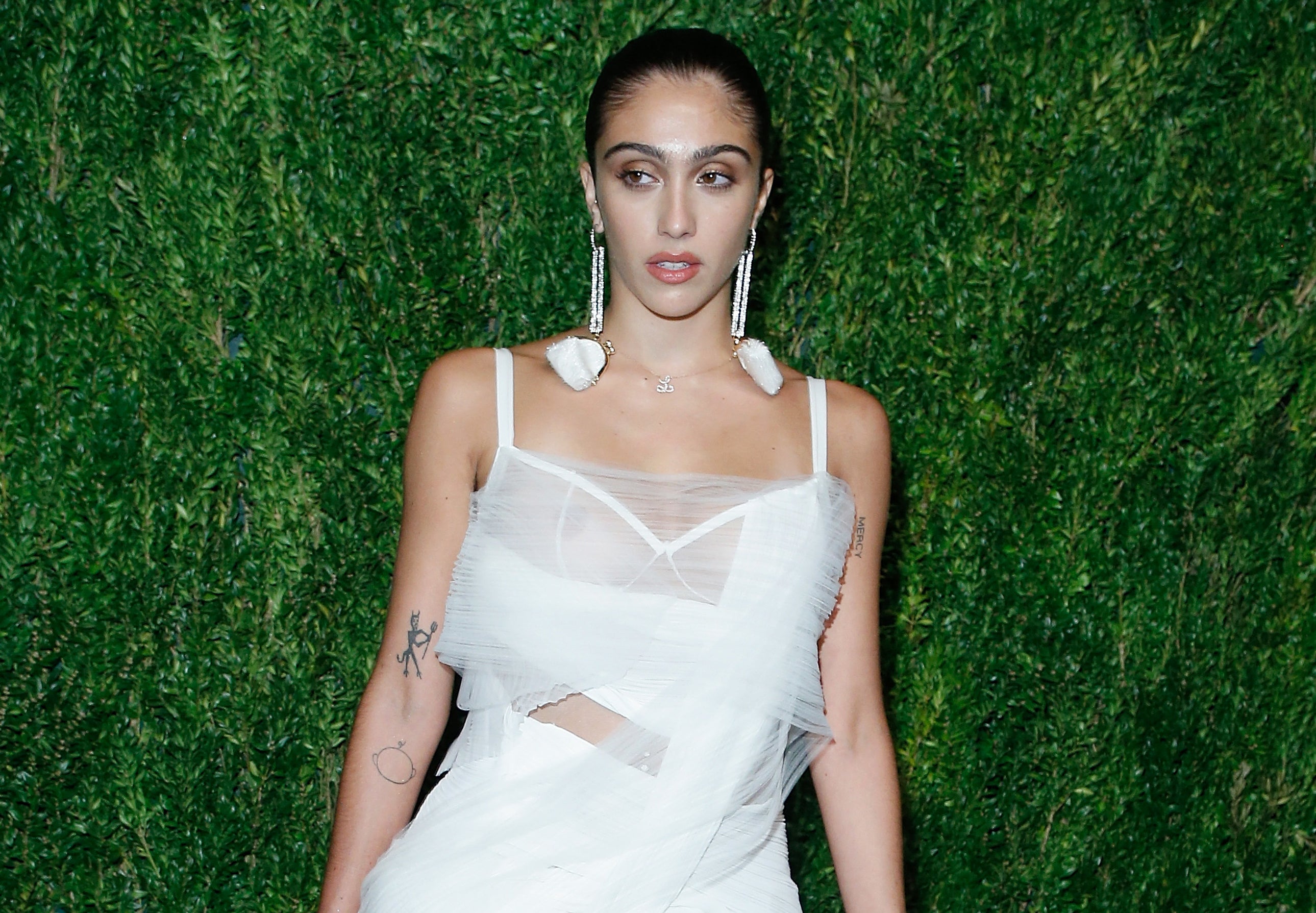Lourdes wears a white dress while on a red carpet 