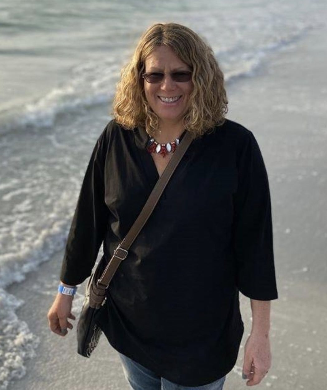 a reviewer walking on a beach wearing a black tunic shirt