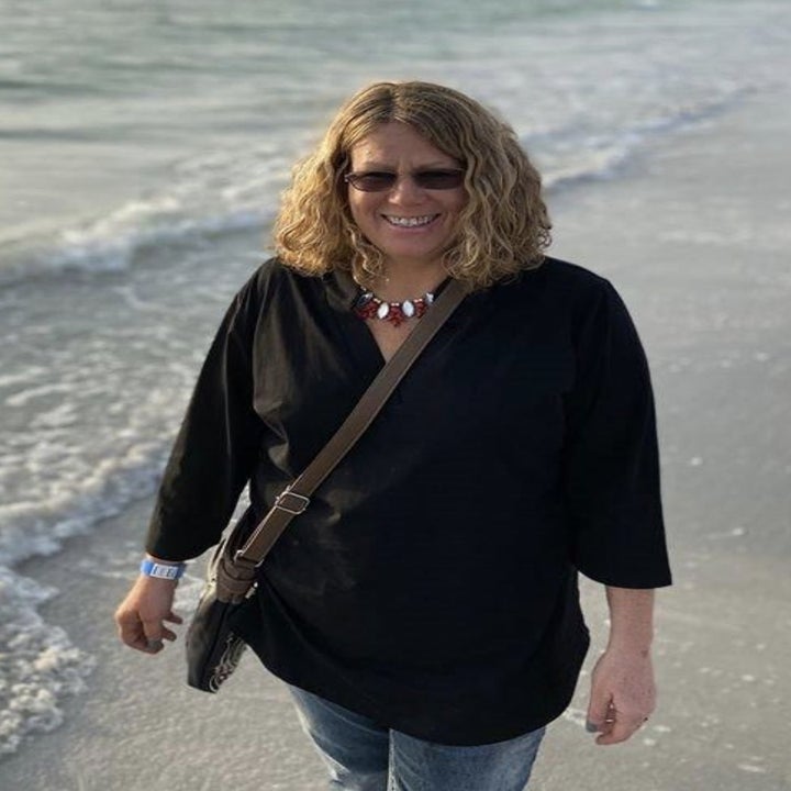 a reviewer walking on a beach wearing a black tunic shirt