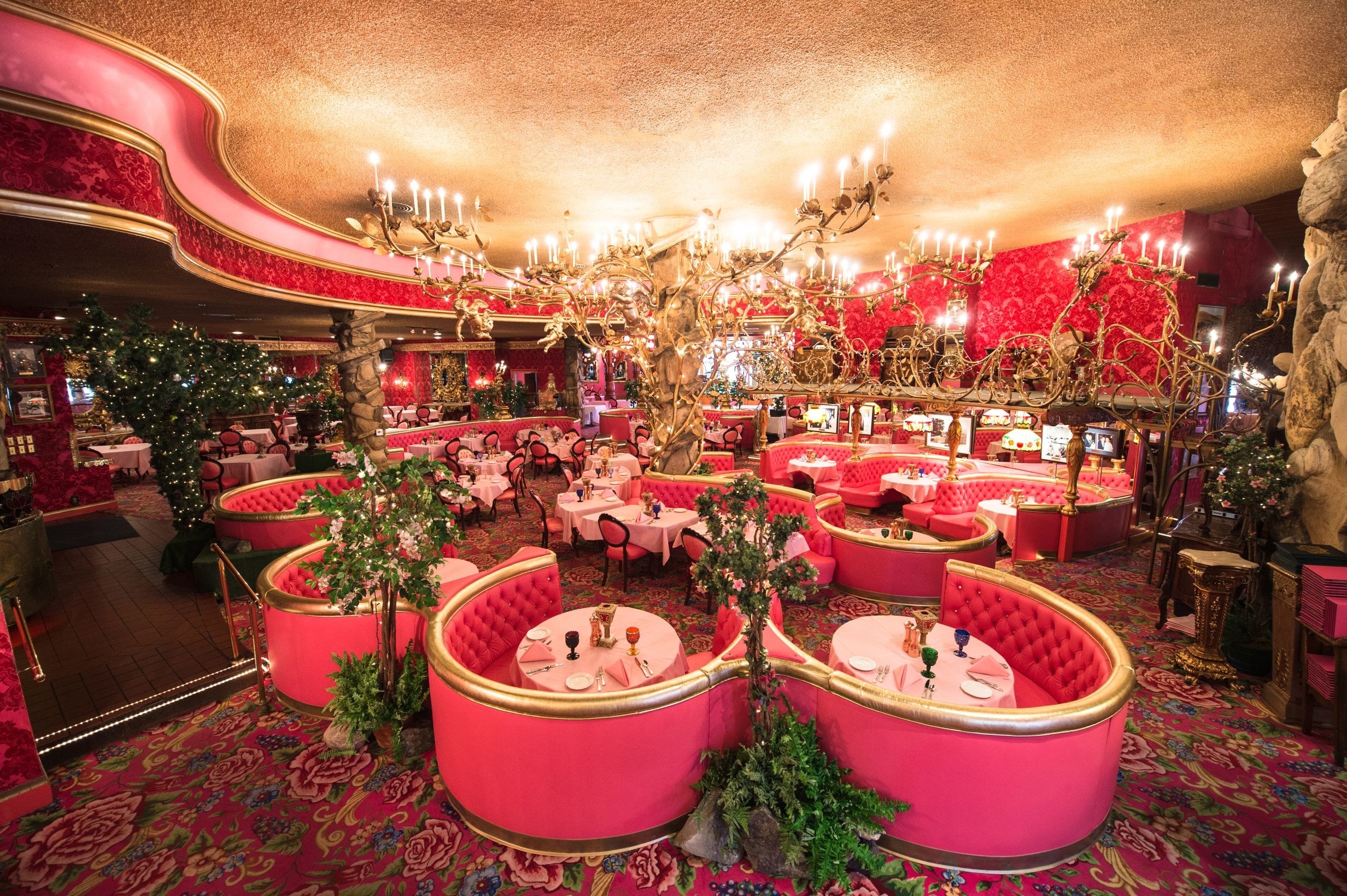 A hotel dining room with bright pink booths and chandeliers 