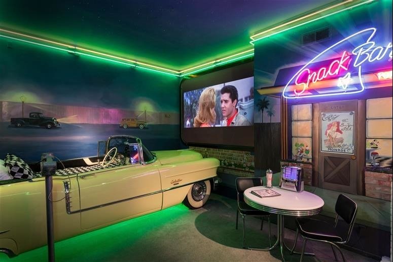A neon-lit hotel room with a bed shaped like a car