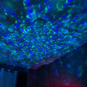 reviewer image of a bedroom whose walls and ceiling are covered in blue and green LED ocean wave lights