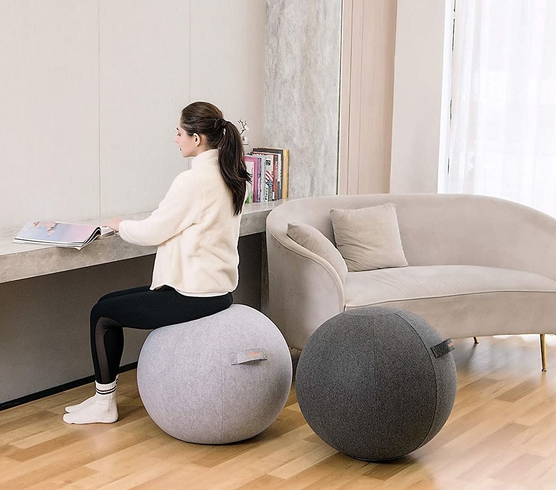 A person sitting on a ball next to a second ball in a living room 