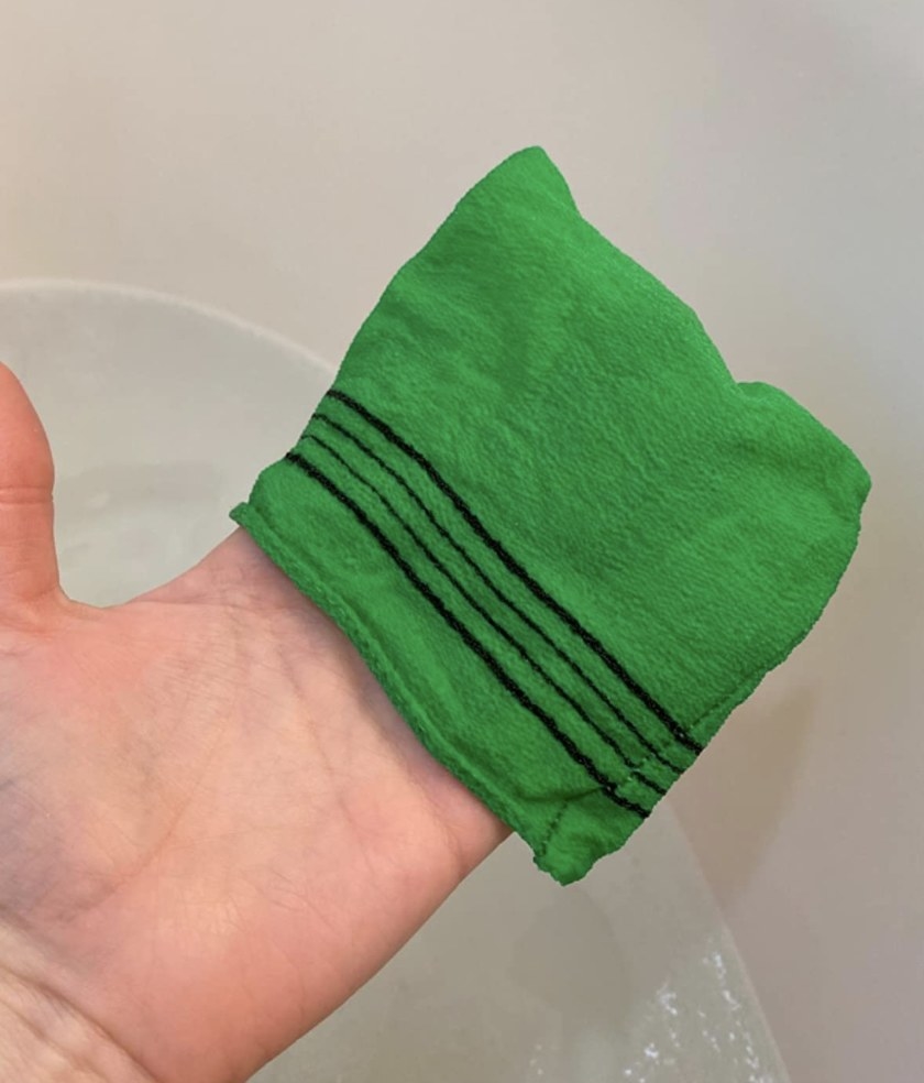 A person holding a green washcloth