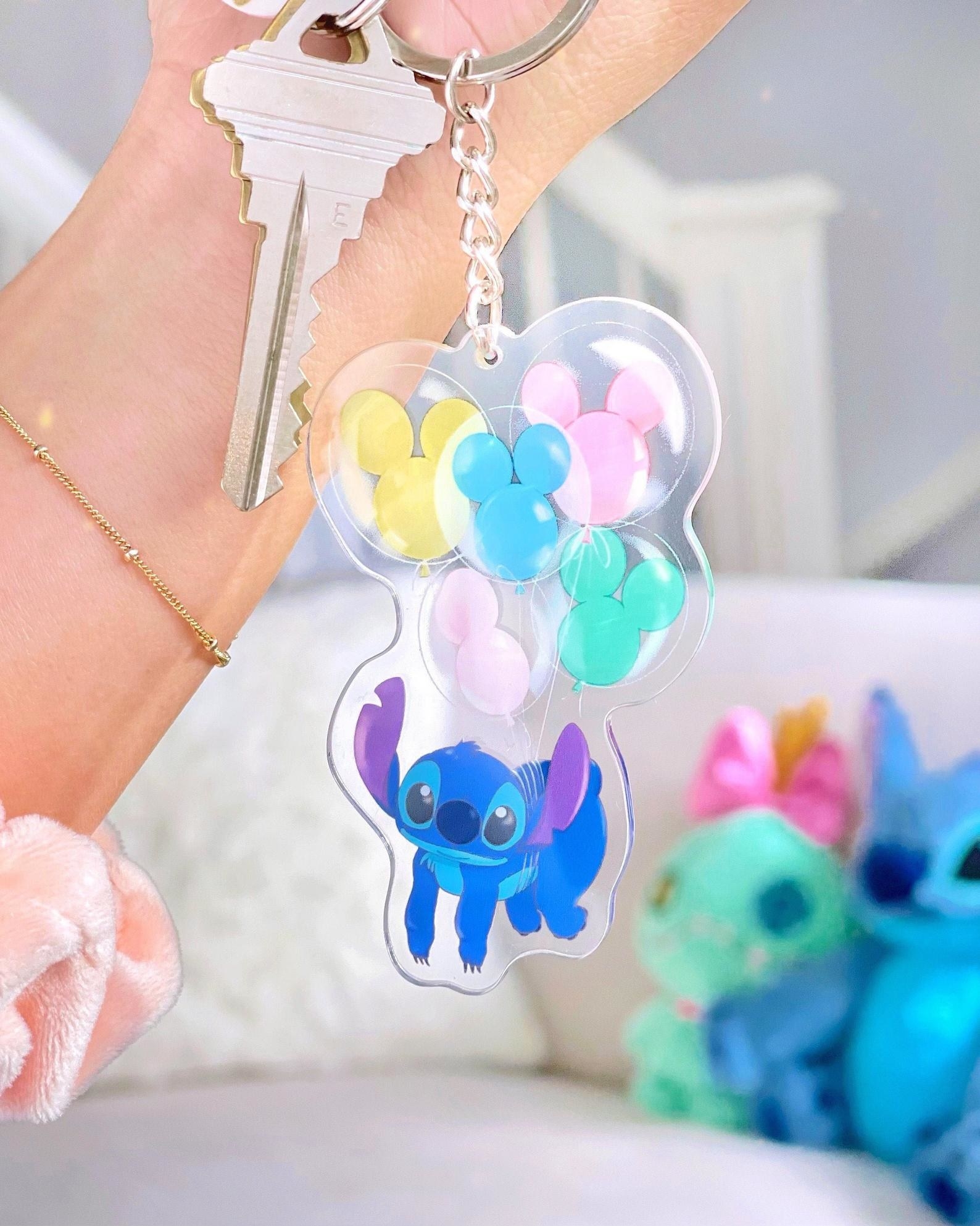 a keychain of stitch floating from mickey shaped balloons