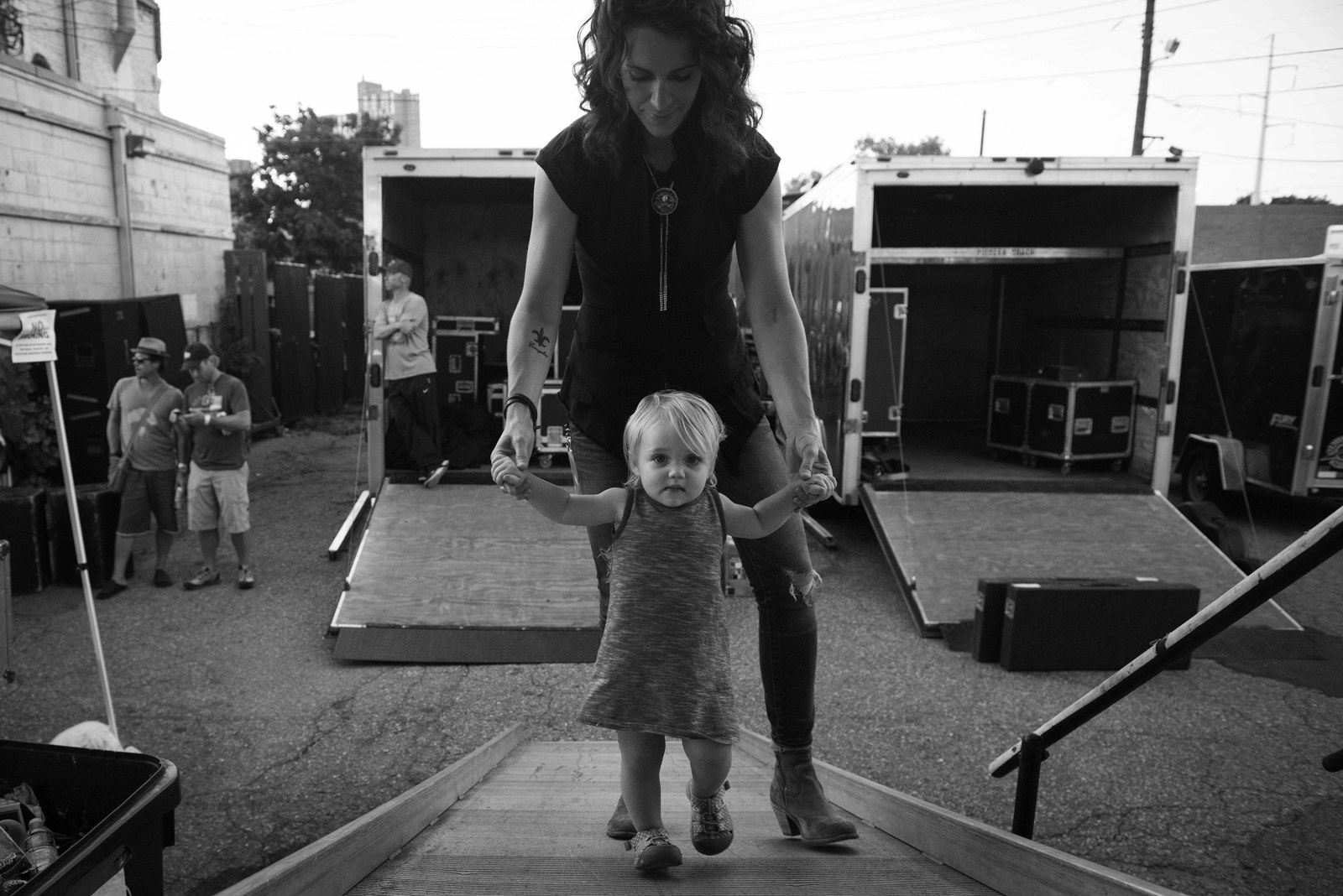 A mother walks behind her toddler child up a ramp