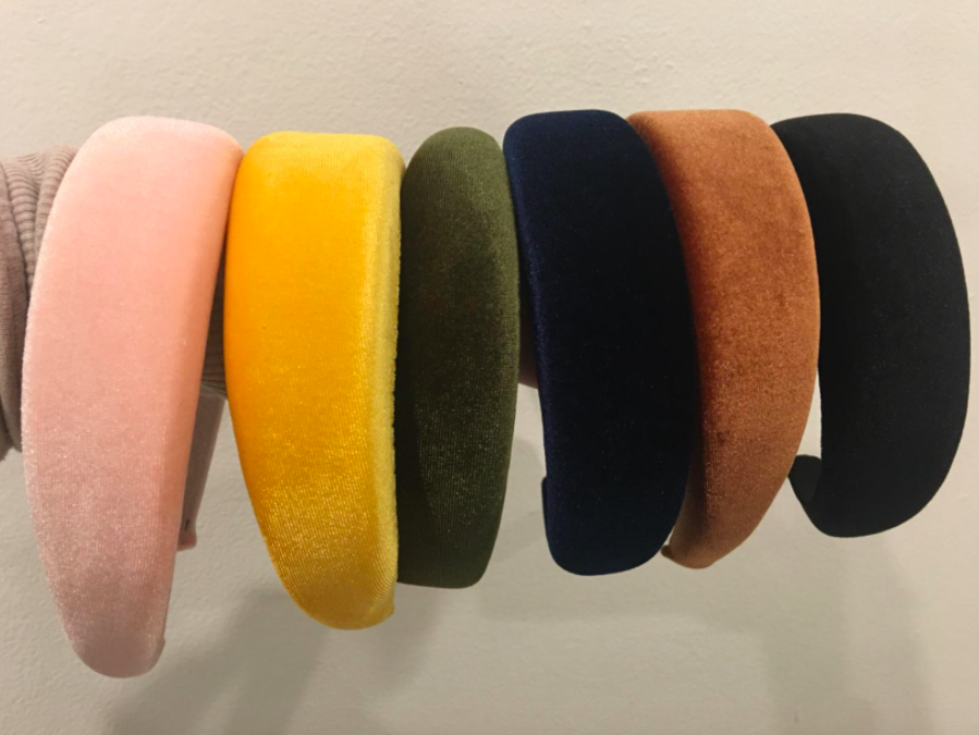 A customer review photo of pink, gold, green, navy, brown, and black velvet headbands.