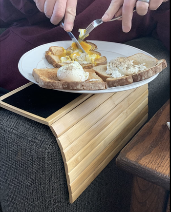 Reviewer using the tray on the arm of a couch to eat a plate of eggs and toast