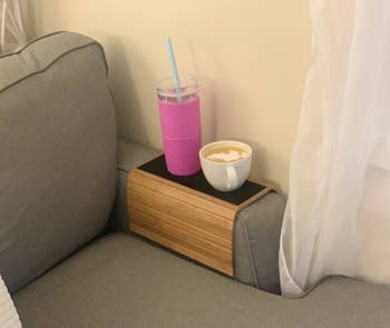 Reviewer using flexible wood tray draped over a couch arm with a mug and water bottle on it 