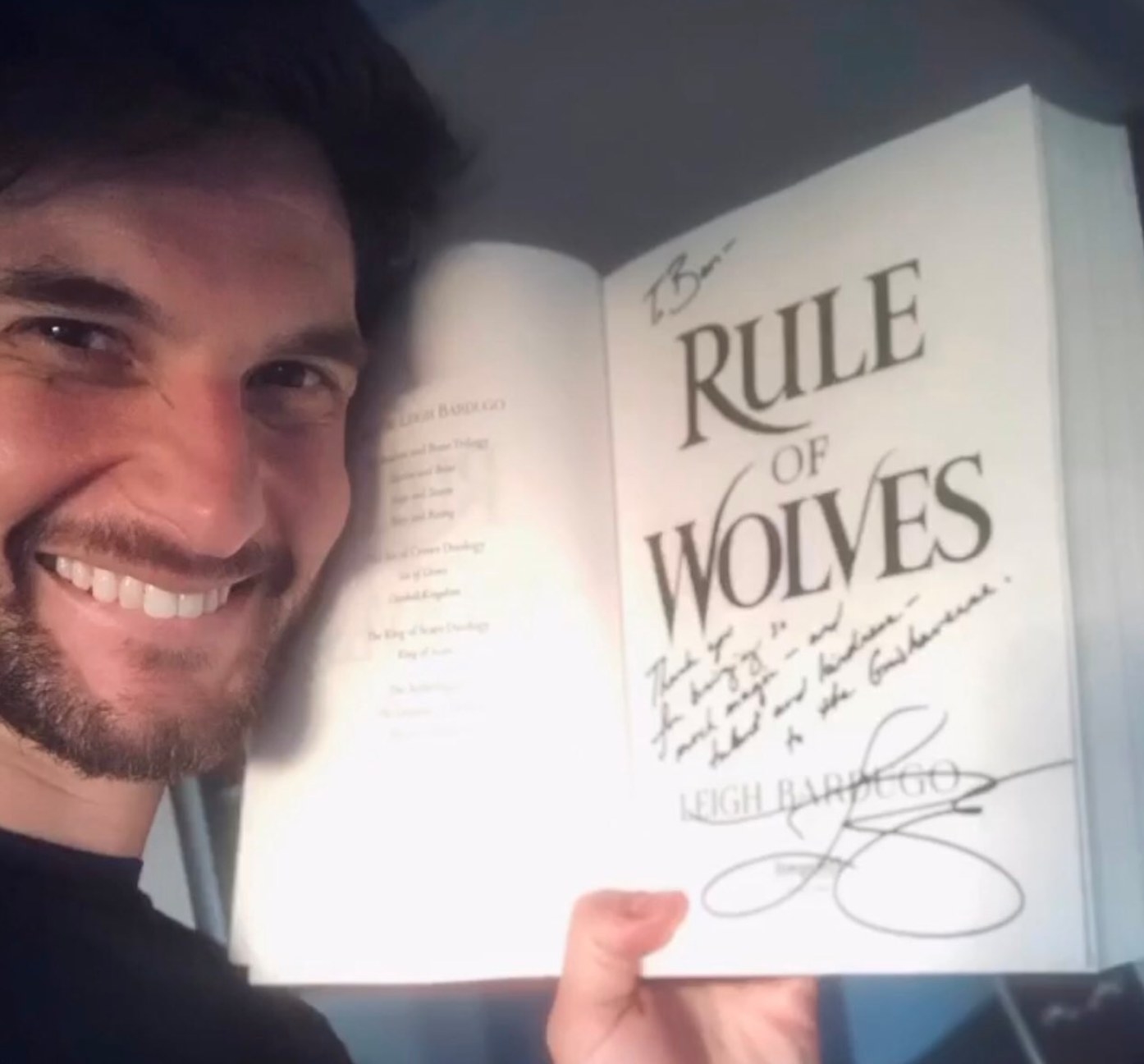 Ben Barnes holding a copy of Rule of Wolves by Leigh Bardugo