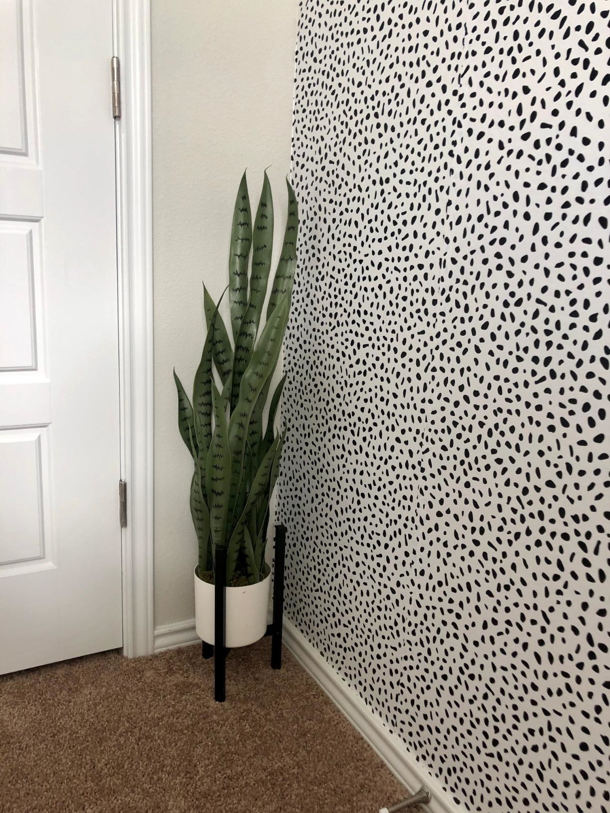 Reviewer&#x27;s photo of a faux snake plant with white pot and black pot stand