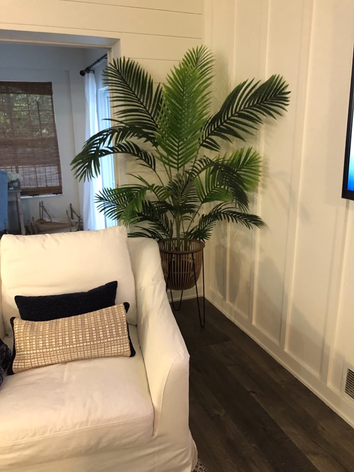 Reviewer&#x27;s photo of a five-foot-tall Areca Palm plant in a white pot with wooden stand