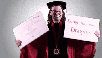 Woman wearing a graduation cap and gown and holding up a diploma and a &quot;Congratulations, Dragons!&quot; sign