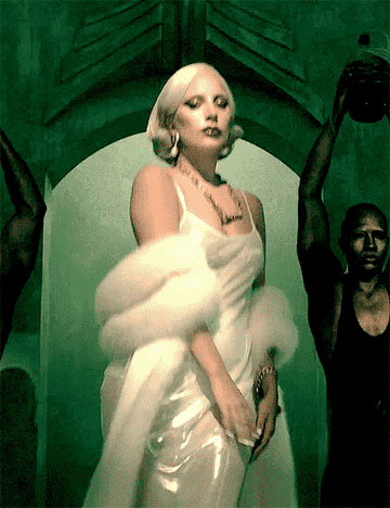 GIF of Lady Gaga in a sheer gown and fur wrap