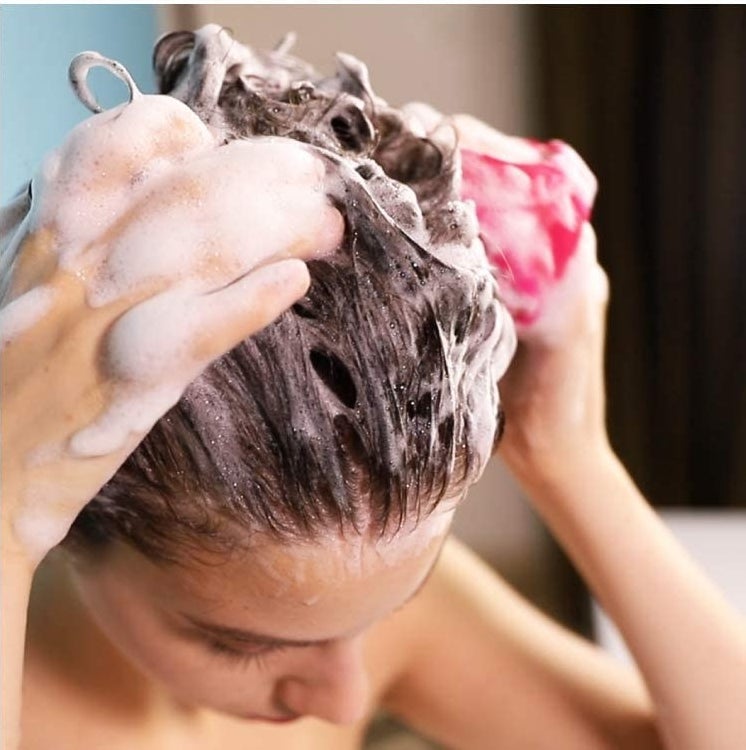 A person using the brush while washing their hair.