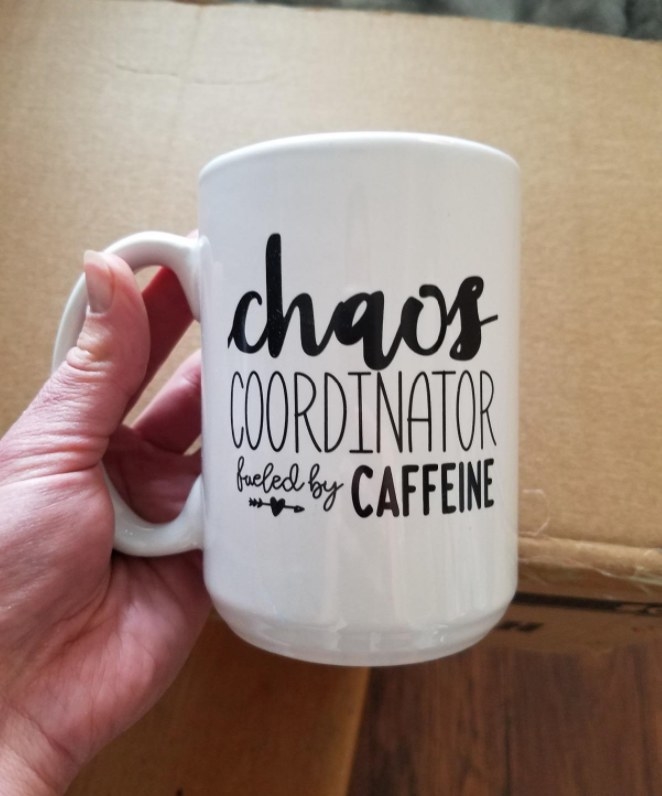 A reviewer holding the mug which reads, &quot;chaos coordinator fueled by caffeine&quot; 