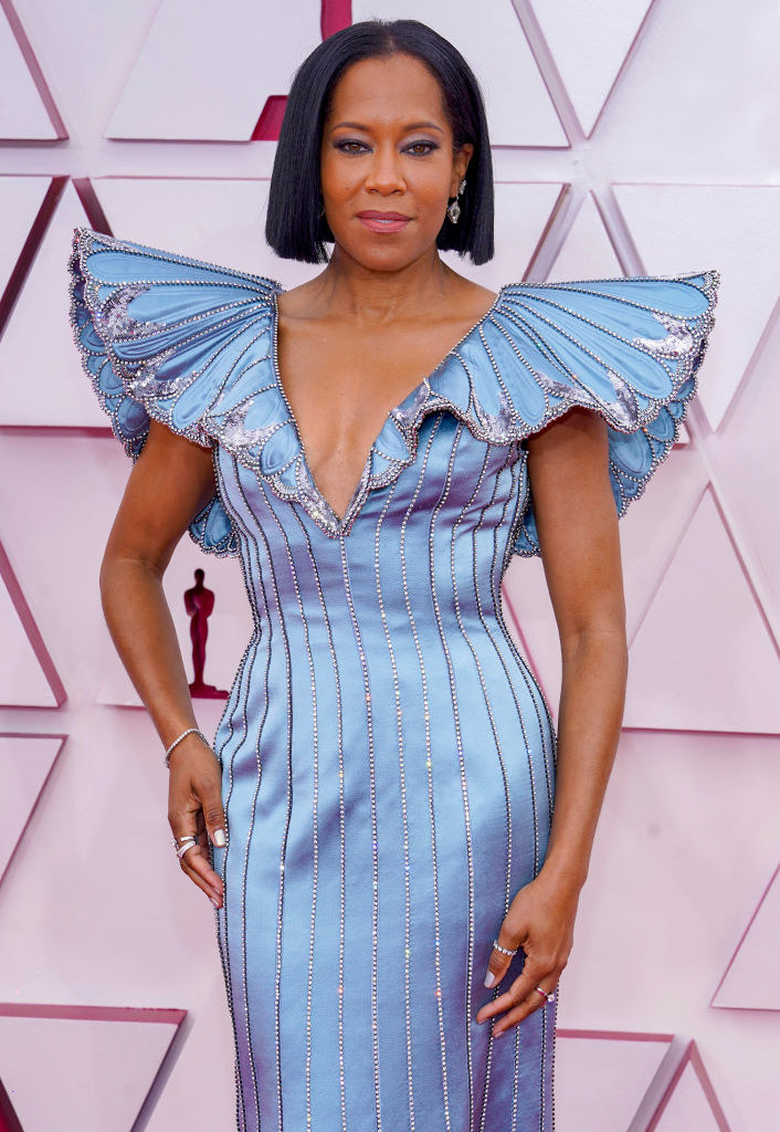 Regina King wearing a long, straight blue gown with winged shoulders