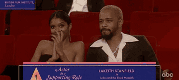 LaKeith claps while sitting in the audience 
