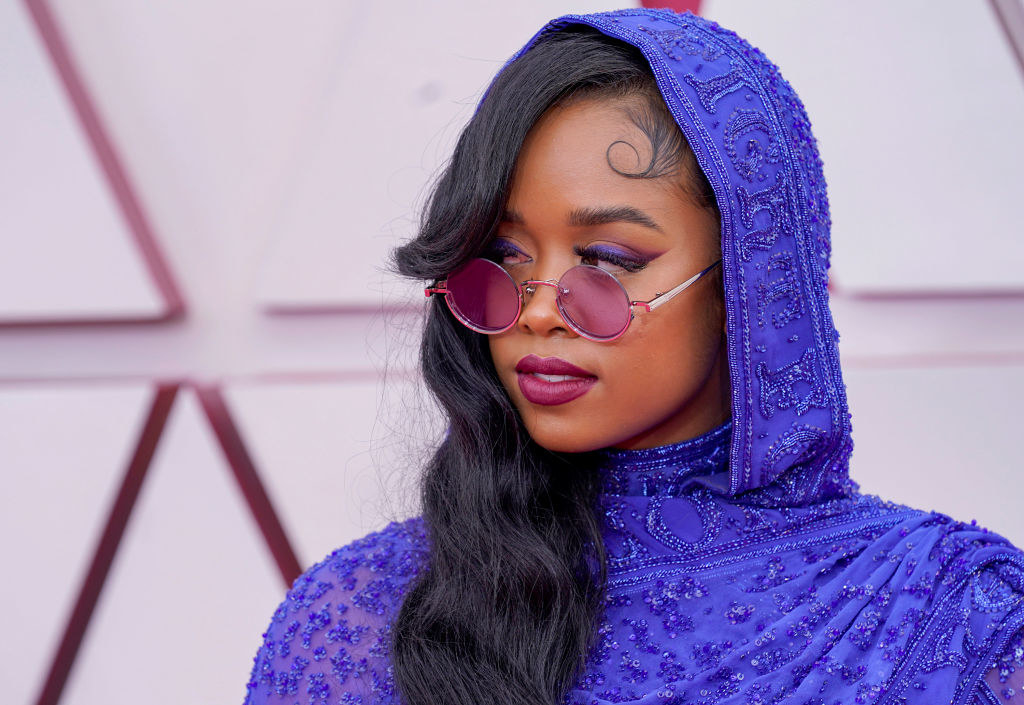 H.E.R. in a blue hooded outfit and wearing sunglasses