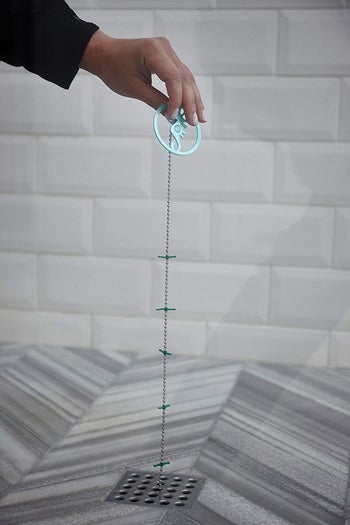 person pulling out hair catching device from shower drain