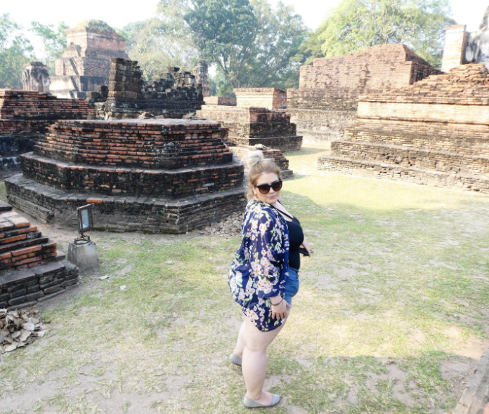 plus size reviewer at a tourist site of ruins wearing shorts