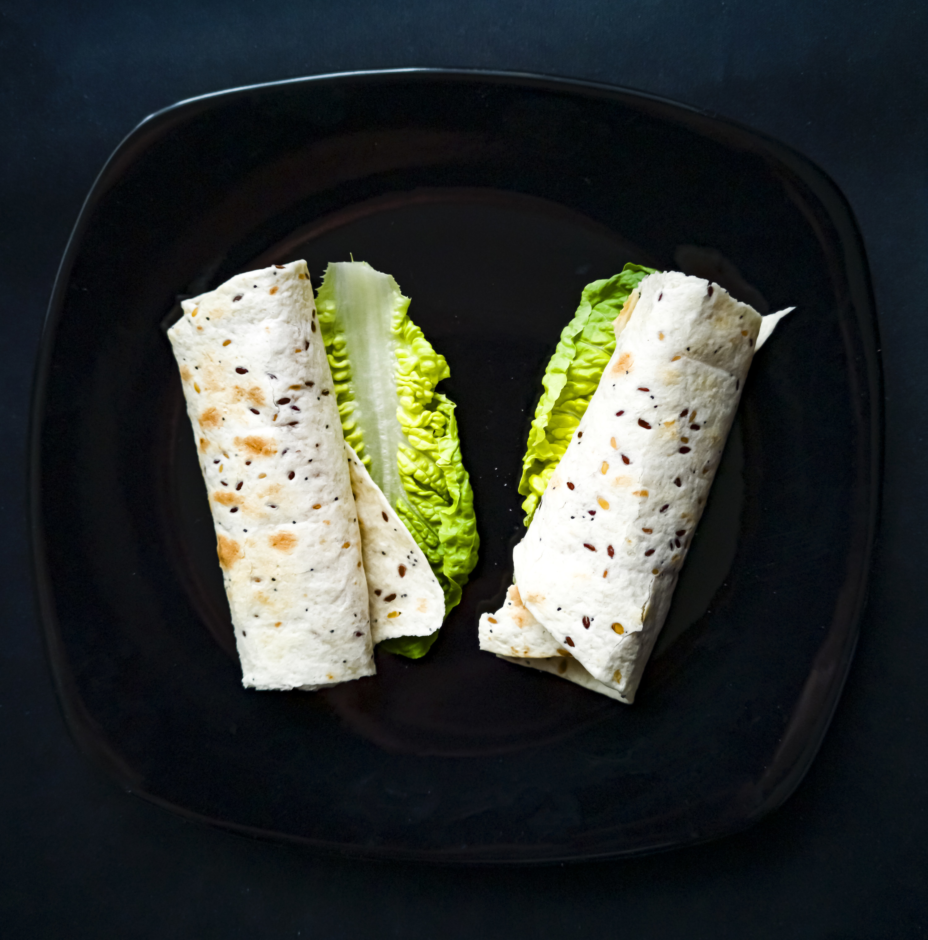 An image of tortillas rolled with ingredients inside, on top of a stove