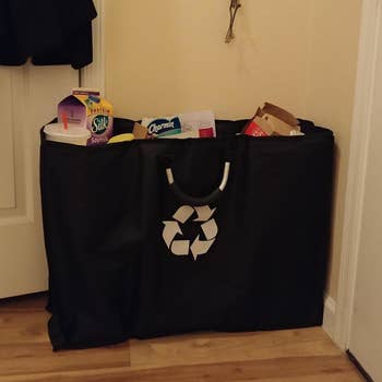 a reviewer photo of the black tote with a white recycling symbol on it 