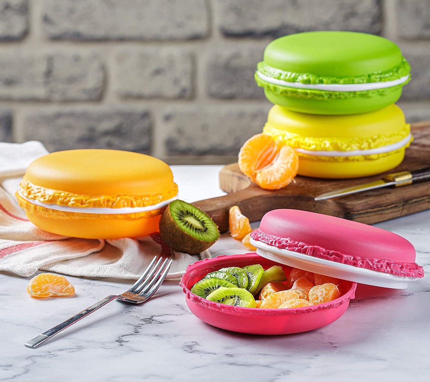 four macaron-shaped containers in orange, yellow, green, and pink