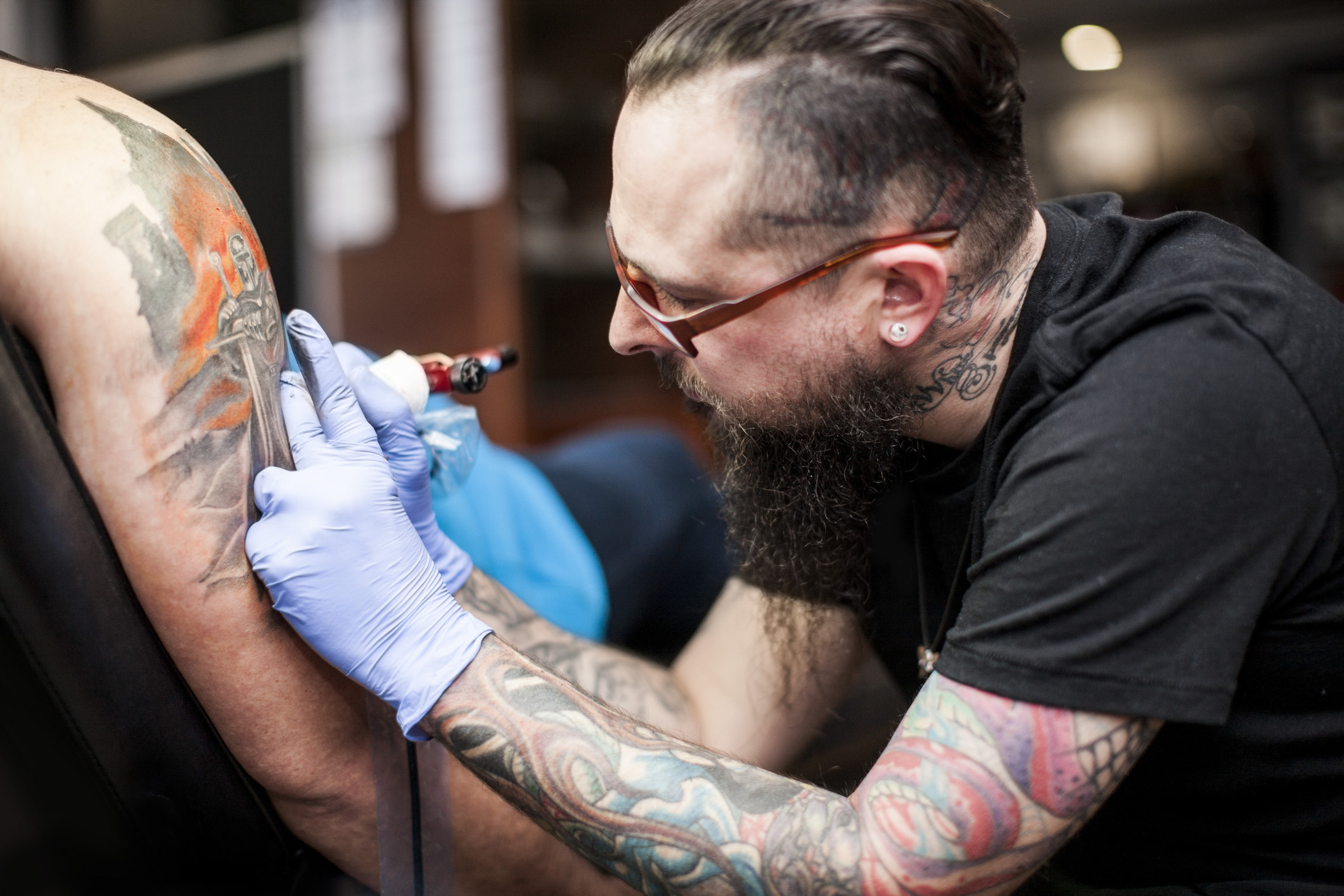 a tattoo artist working on an arm